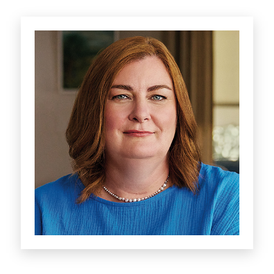 A picture of a woman in a blue shirt wearing a shiny necklace